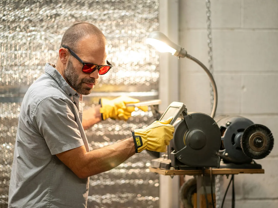 Opérateur portant des lunettes de protection et des gants devant un touret à meuler